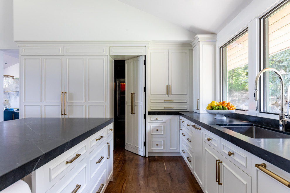 Exempel på ett mycket stort modernt svart svart u-kök, med en undermonterad diskho, släta luckor, vita skåp, marmorbänkskiva, vitt stänkskydd, stänkskydd i marmor, integrerade vitvaror, mellanmörkt trägolv, flera köksöar och brunt golv