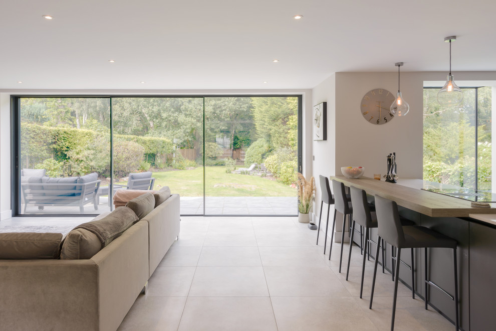 This is an example of a mid-sized contemporary single-wall open plan kitchen in Other with an integrated sink, flat-panel cabinets, grey cabinets, white splashback, panelled appliances, porcelain floors, with island, beige floor and white benchtop.