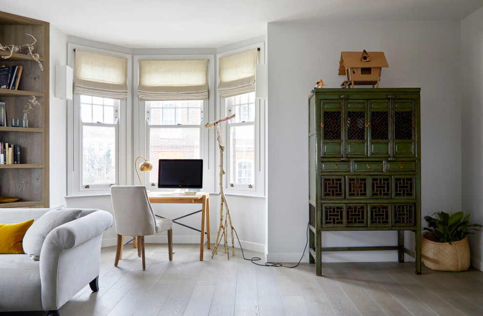 Inspiration for a large country study room in London with beige walls, medium hardwood floors, a wood stove, a stone fireplace surround, a freestanding desk and brown floor.