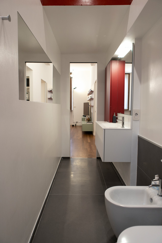 Idée de décoration pour une salle de bain longue et étroite minimaliste de taille moyenne avec un placard à porte plane, des portes de placard rouges, WC séparés, un carrelage rouge, un carrelage de pierre, un mur rouge, un sol en carrelage de porcelaine, un lavabo posé, un plan de toilette en quartz modifié, un sol gris, aucune cabine, un plan de toilette blanc, meuble simple vasque et meuble-lavabo suspendu.