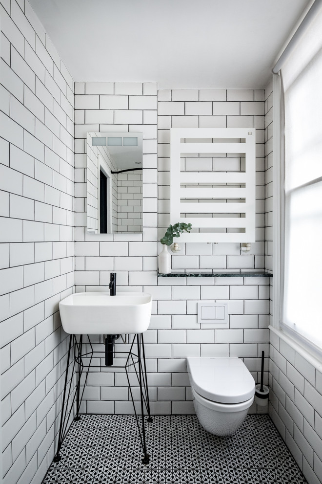 Design ideas for a small eclectic powder room in London with a wall-mount toilet, white tile, subway tile, white walls, ceramic floors, a pedestal sink, marble benchtops, multi-coloured floor, green benchtops and a freestanding vanity.