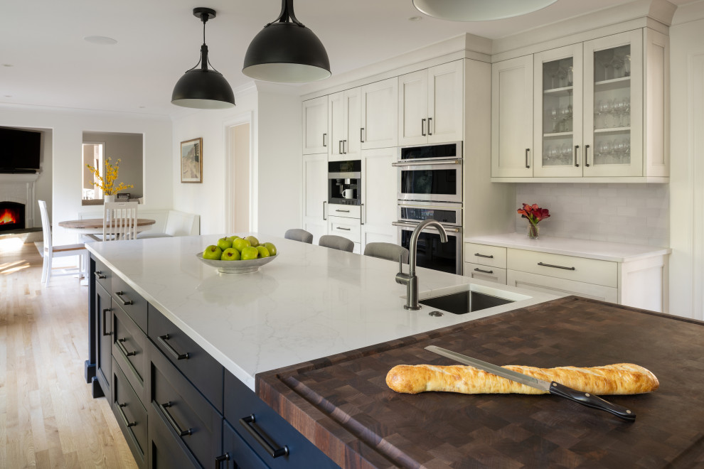 Enclosed kitchen - large transitional u-shaped light wood floor enclosed kitchen idea in DC Metro with an undermount sink, shaker cabinets, white cabinets, quartzite countertops, white backsplash, subway tile backsplash, stainless steel appliances, an island and white countertops