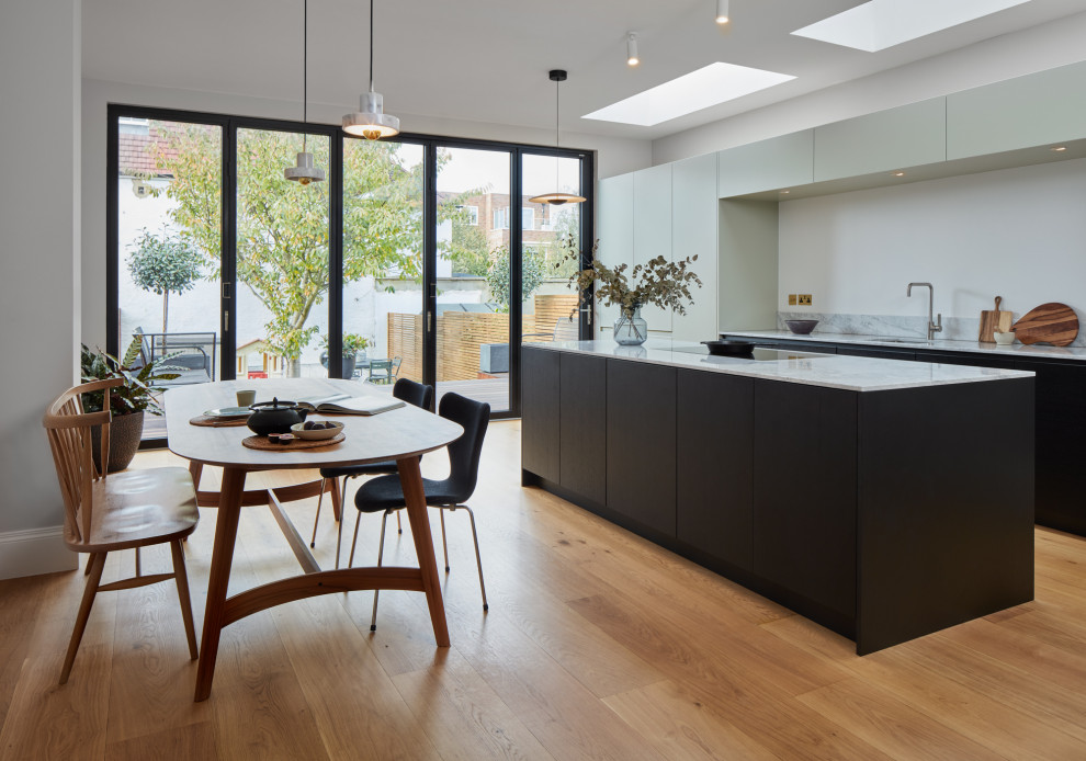 Design ideas for a large contemporary kitchen in London with a submerged sink, flat-panel cabinets, black cabinets, marble worktops, marble splashback, black appliances, dark hardwood flooring, an island and feature lighting.