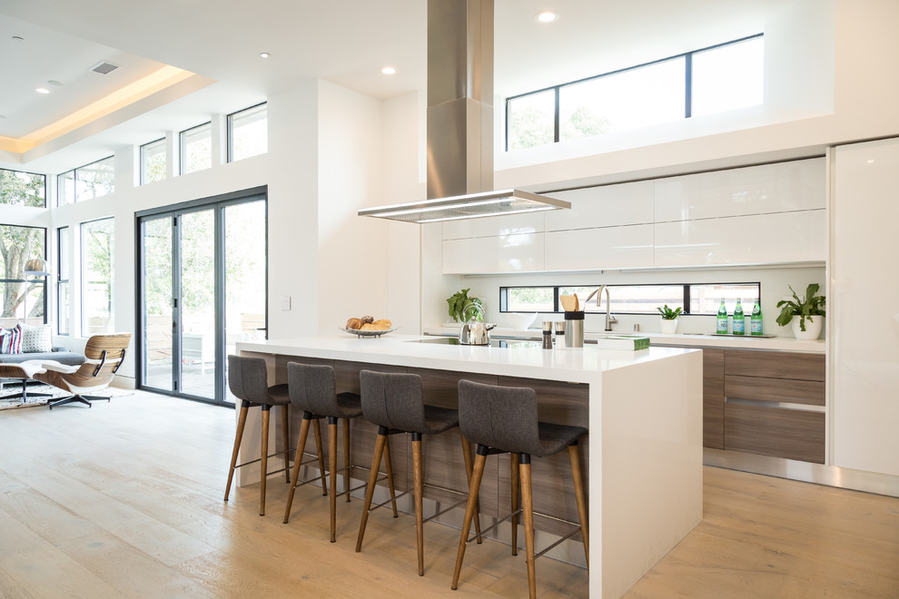 Design ideas for a large modern open plan kitchen in San Francisco with an undermount sink, flat-panel cabinets, white cabinets, quartz benchtops, white splashback, white appliances, light hardwood floors, with island and brown floor.
