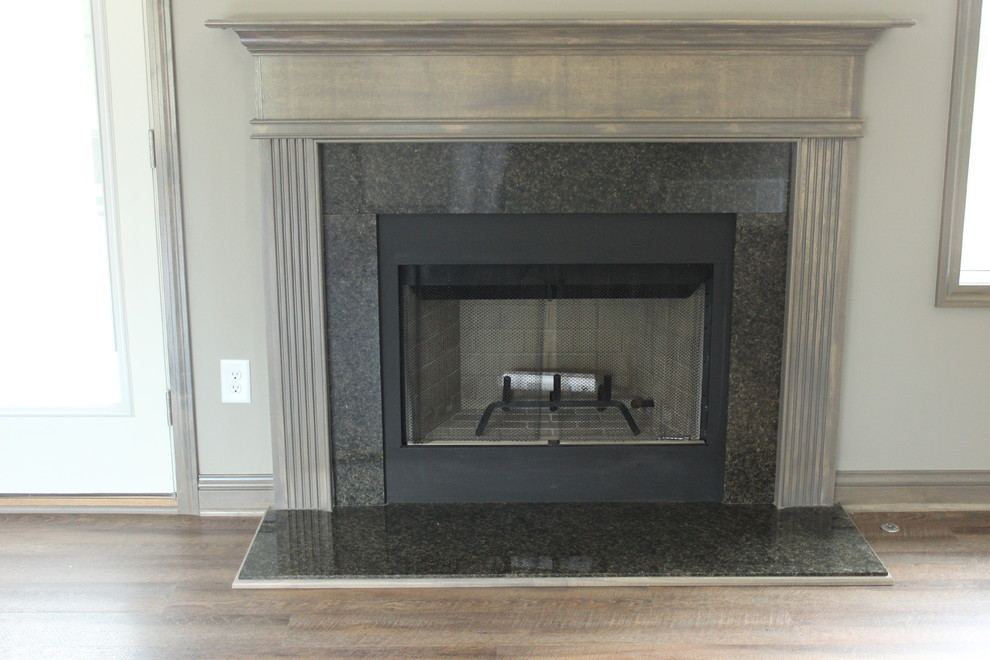 This is an example of a traditional living room in Columbus with grey walls, a standard fireplace, a stone fireplace surround and beige floor.