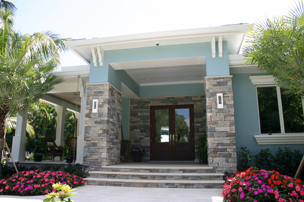 This is an example of a mid-sized beach style one-storey stucco blue house exterior in Miami with a hip roof and a metal roof.