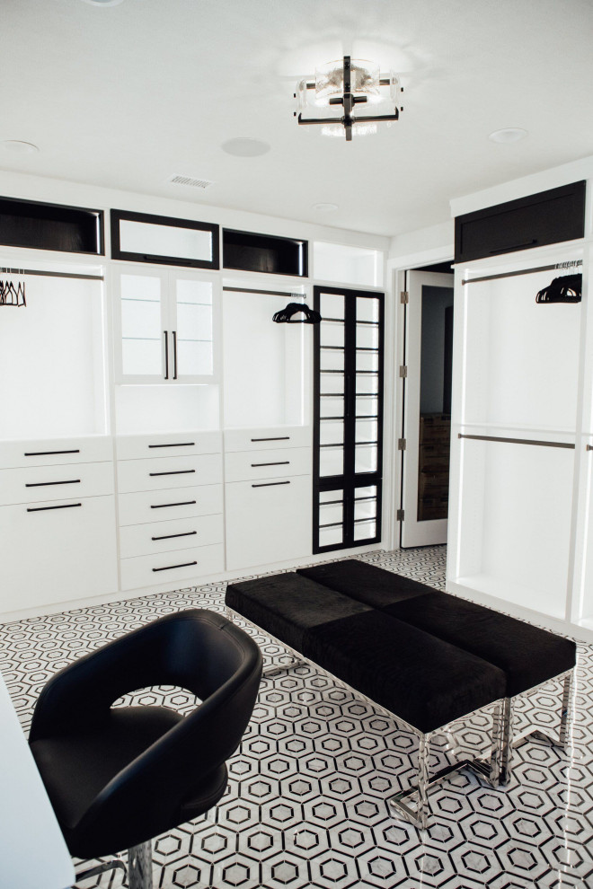 Expansive modern gender neutral walk-in wardrobe in Orange County with flat-panel cabinets, white cabinets, carpet, multi-coloured floors and a vaulted ceiling.