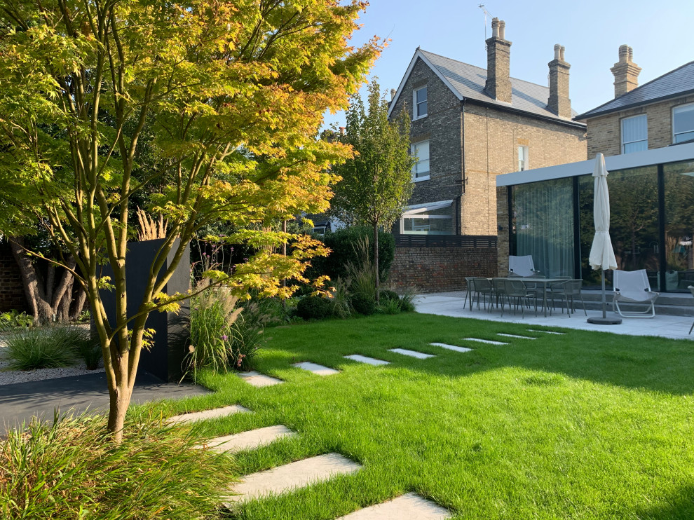 Immagine di un giardino contemporaneo esposto in pieno sole di medie dimensioni e dietro casa in estate con pavimentazioni in pietra naturale e recinzione in legno