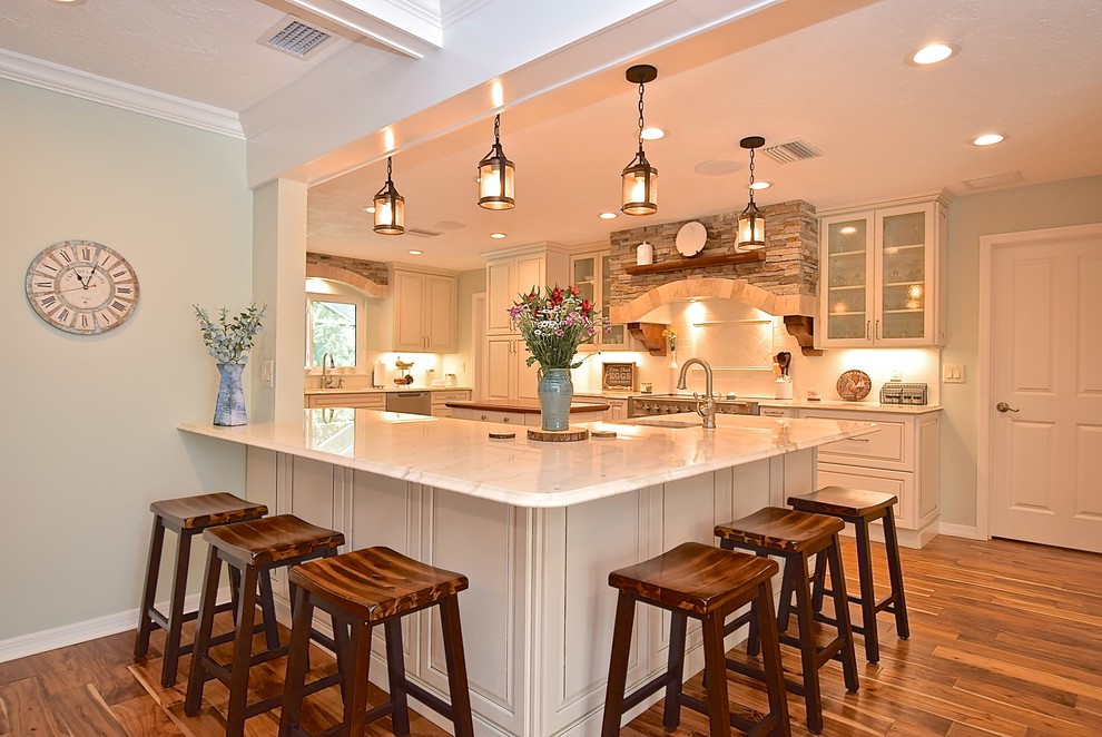 Photo of a large country kitchen in Tampa with a single-bowl sink, raised-panel cabinets, white cabinets, quartzite benchtops, white splashback, stainless steel appliances, dark hardwood floors, with island and white benchtop.