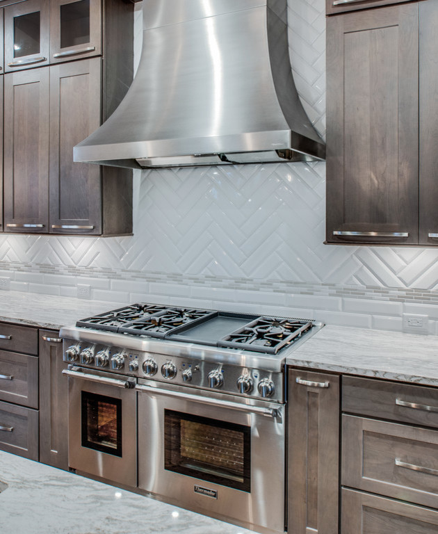 Inspiration for a mid-sized transitional l-shaped dark wood floor and brown floor enclosed kitchen remodel in Nashville with an undermount sink, shaker cabinets, dark wood cabinets, granite countertops, white backsplash, porcelain backsplash, stainless steel appliances and an island