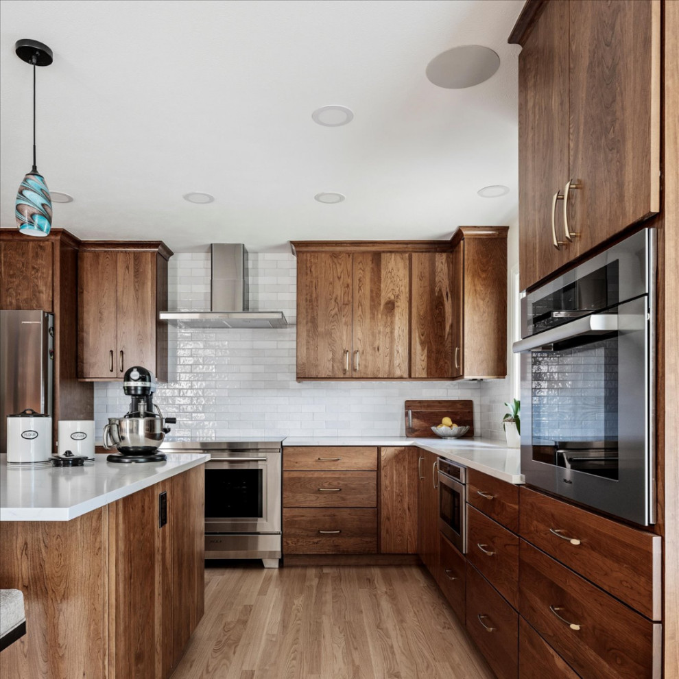 Eat-in kitchen - large transitional l-shaped light wood floor and brown floor eat-in kitchen idea in Denver with an undermount sink, flat-panel cabinets, medium tone wood cabinets, quartzite countertops, white backsplash, ceramic backsplash, stainless steel appliances, an island and white countertops