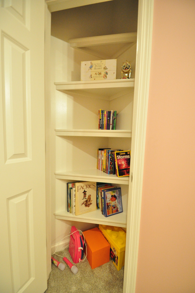 This is an example of a small transitional gender-neutral built-in wardrobe in Other with white cabinets, carpet and beige floor.