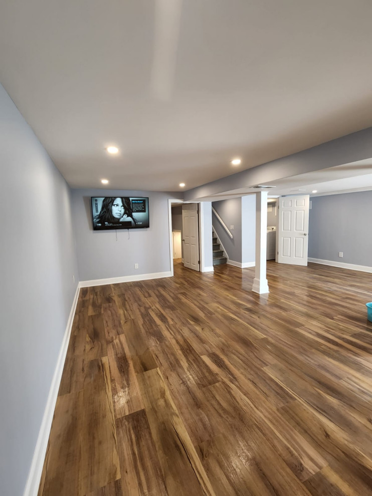 Diseño de sótano moderno grande con bar en casa, paredes grises, suelo vinílico y suelo marrón
