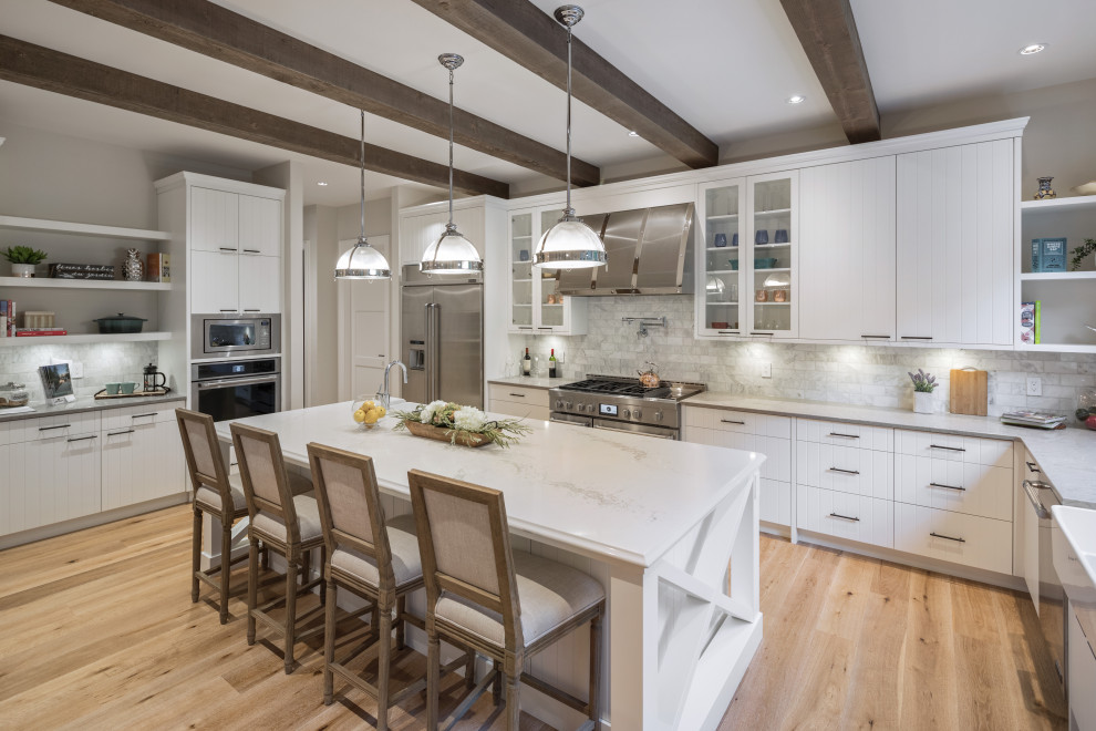 Eat-in kitchen - mid-sized transitional l-shaped light wood floor and beige floor eat-in kitchen idea with a farmhouse sink, flat-panel cabinets, white cabinets, marble countertops, gray backsplash, marble backsplash, stainless steel appliances, an island and gray countertops