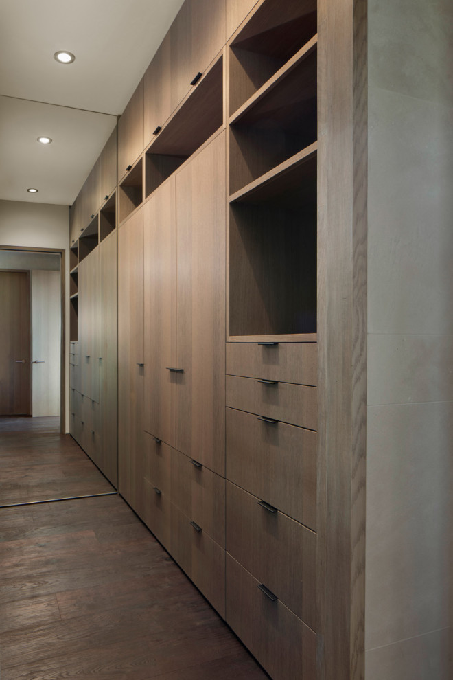 На фото: встроенный шкаф среднего размера в стиле модернизм с плоскими фасадами, фасадами цвета дерева среднего тона, темным паркетным полом и коричневым полом для мужчин с