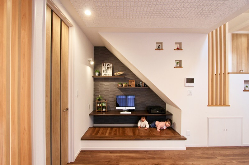 This is an example of a large contemporary open concept living room in Fukuoka with black walls, plywood floors, a freestanding tv and brown floor.