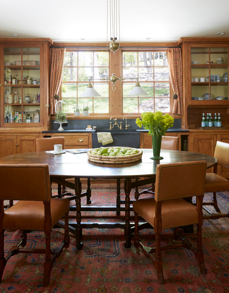 This is an example of a traditional eat-in kitchen in New York with a farmhouse sink, glass-front cabinets and medium wood cabinets.
