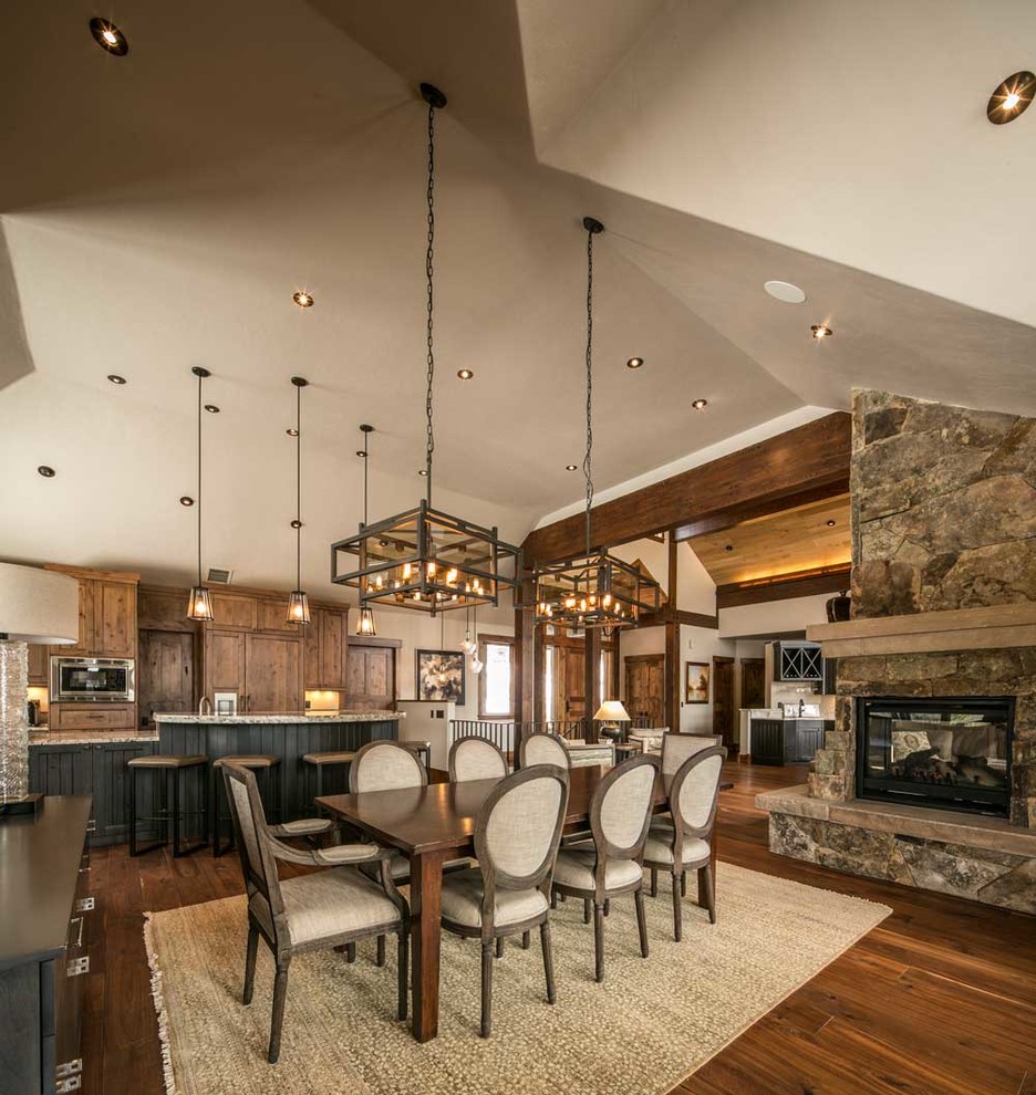 Large country open plan dining in Denver with a stone fireplace surround, brown walls, dark hardwood floors and a corner fireplace.