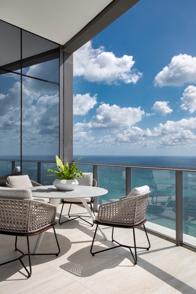 Example of a trendy glass railing balcony design in Miami with a roof extension