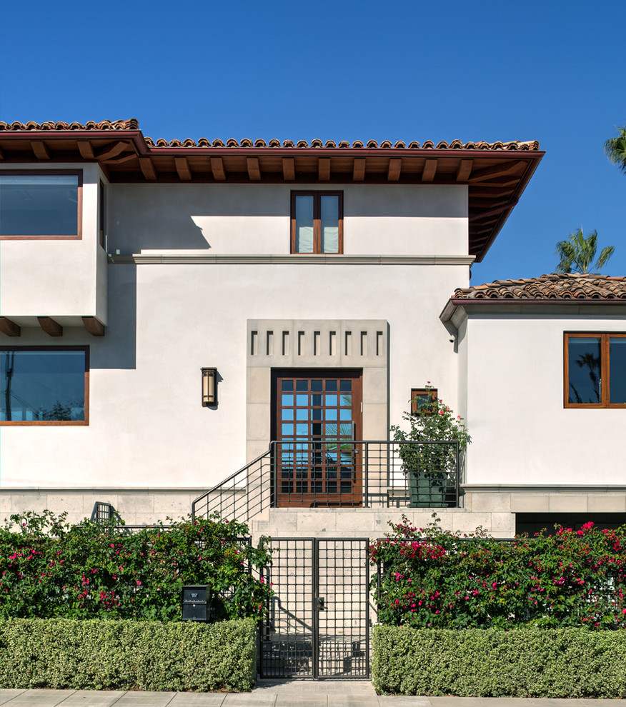 Large mediterranean three-storey white exterior in San Diego with stone veneer and a hip roof.