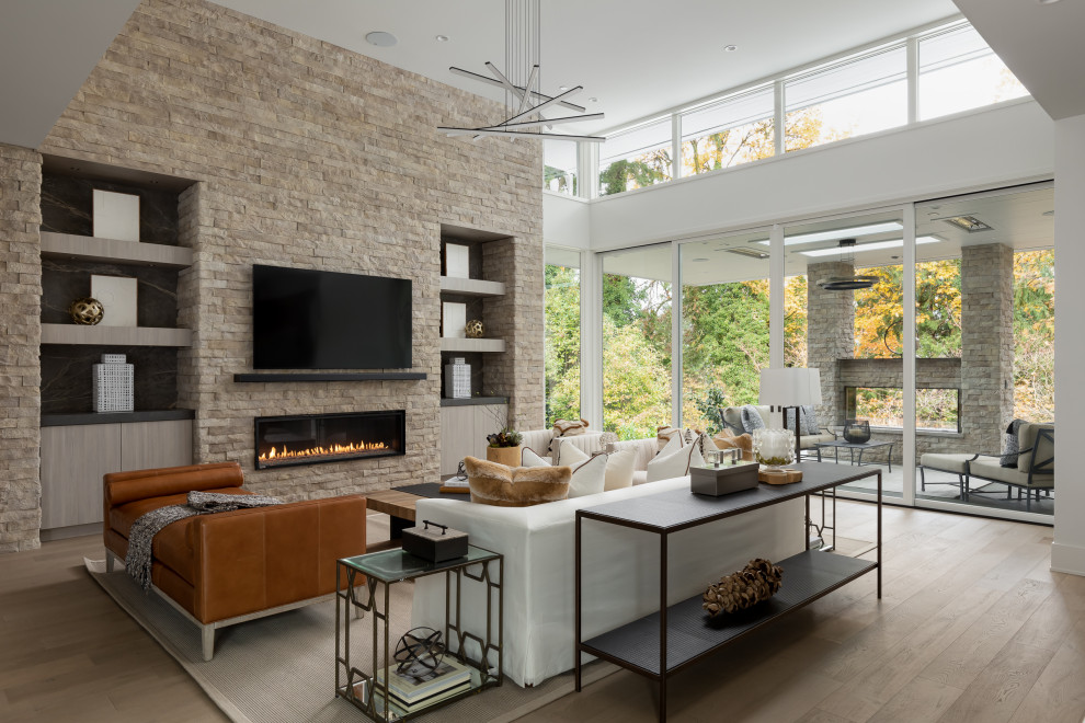 Offenes Modernes Wohnzimmer mit hellem Holzboden, Gaskamin, Kaminumrandung aus gestapelten Steinen, TV-Wand und beigem Boden in Seattle
