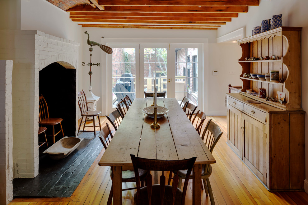 Photo of a large country separate dining room in Boston with white walls, medium hardwood floors, a standard fireplace and a brick fireplace surround.