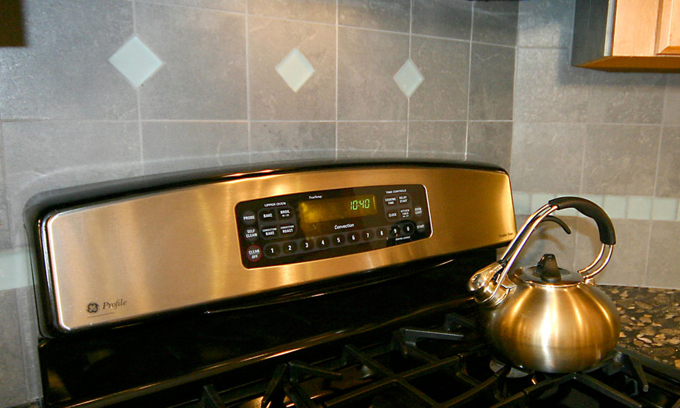 Example of a mid-sized u-shaped medium tone wood floor kitchen pantry design in Boston with an undermount sink, flat-panel cabinets, medium tone wood cabinets, granite countertops, gray backsplash, ceramic backsplash, stainless steel appliances and an island