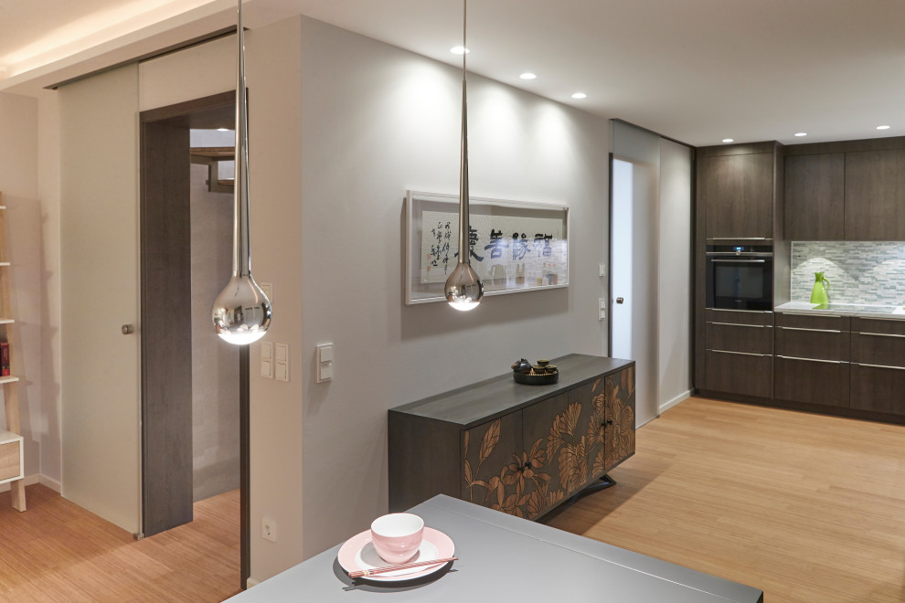 Mittelgroßes, Offenes Asiatisches Wohnzimmer ohne Kamin mit grauer Wandfarbe, Bambusparkett, verstecktem TV und beigem Boden in Düsseldorf