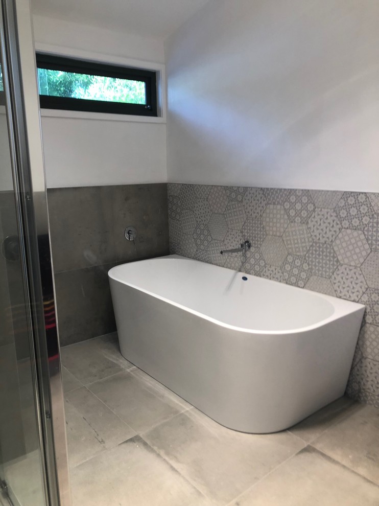 Photo of a large contemporary master bathroom in Melbourne with flat-panel cabinets, white cabinets, a corner tub, a corner shower, a two-piece toilet, gray tile, porcelain tile, white walls, porcelain floors, a vessel sink, granite benchtops, grey floor, a hinged shower door and white benchtops.