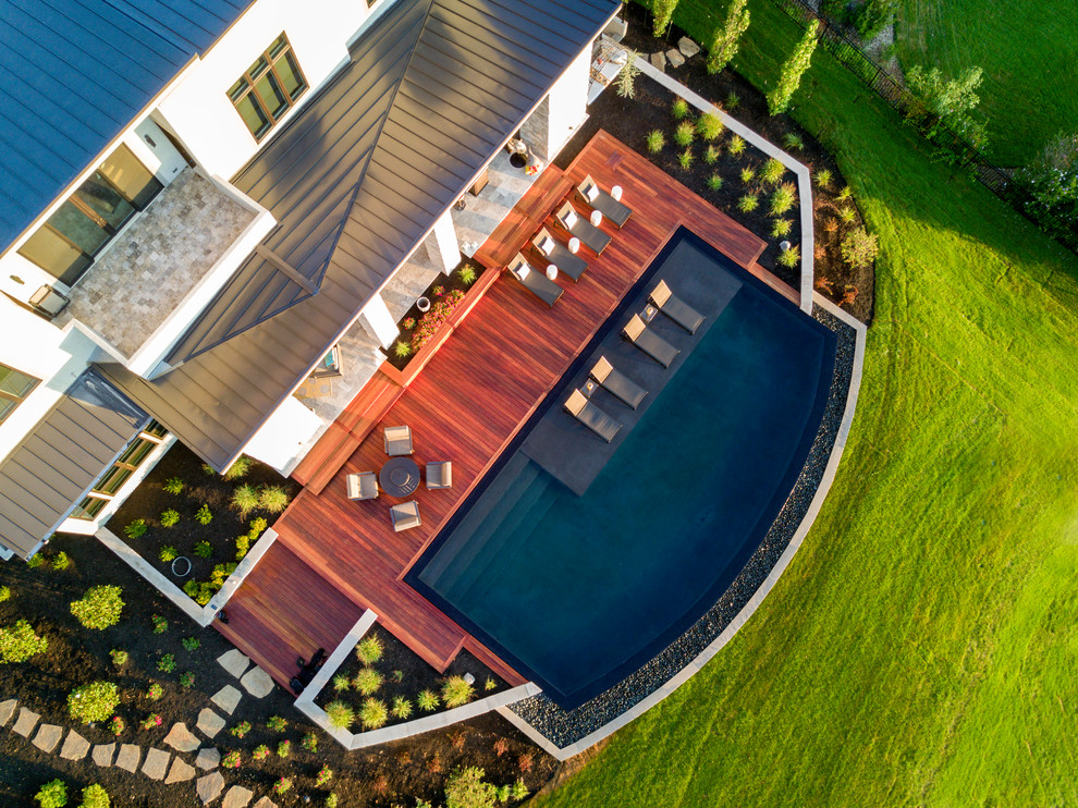 This is an example of a contemporary backyard custom-shaped infinity pool in Kansas City with decking.