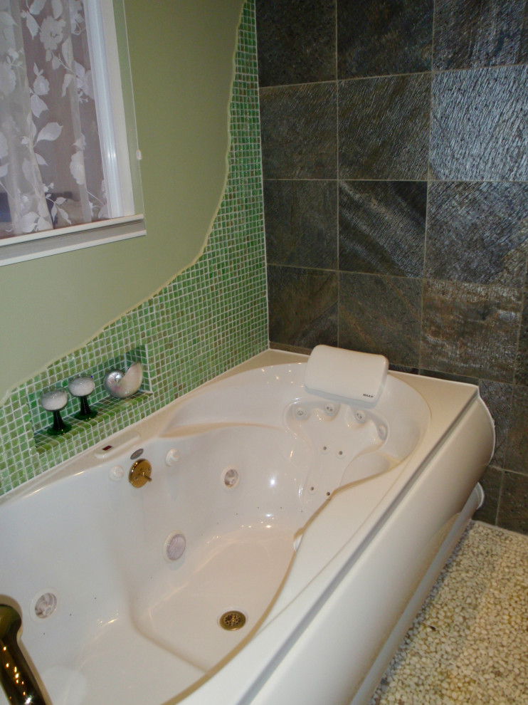 Design ideas for a mid-sized contemporary master wet room bathroom in Other with furniture-like cabinets, light wood cabinets, a drop-in tub, a wall-mount toilet, green tile, slate, green walls, pebble tile floors, a vessel sink, wood benchtops, white floor, an open shower, a niche, a single vanity and a freestanding vanity.