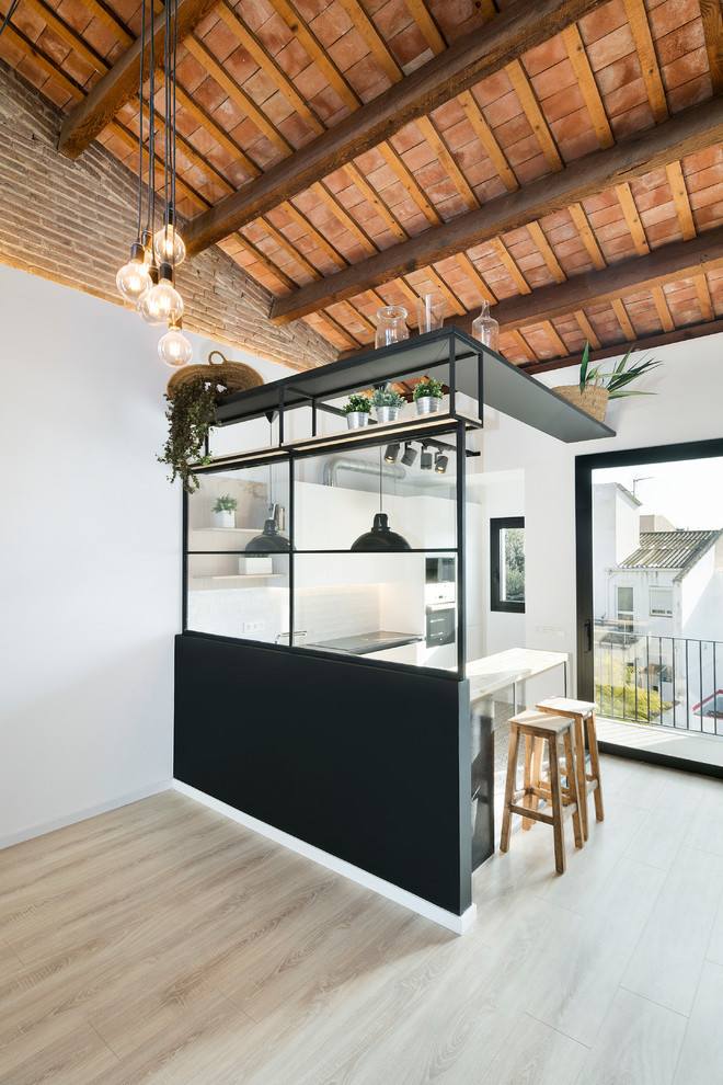 Small industrial galley eat-in kitchen in Barcelona with light hardwood floors and a peninsula.