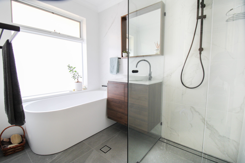 Exempel på ett litet modernt vit vitt en-suite badrum, med släta luckor, skåp i mörkt trä, ett fristående badkar, en hörndusch, vit kakel, porslinskakel, vita väggar, klinkergolv i porslin, ett fristående handfat, bänkskiva i kvarts, grått golv och dusch med gångjärnsdörr