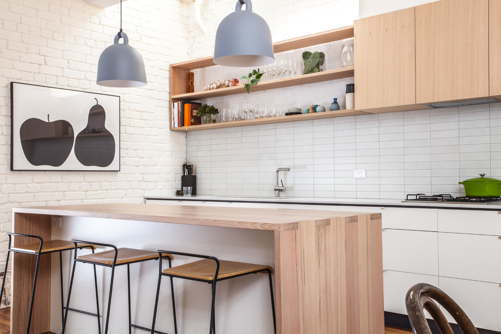 Photo of a mid-sized contemporary single-wall eat-in kitchen in Melbourne with a double-bowl sink, flat-panel cabinets, white cabinets, wood benchtops, white splashback, ceramic splashback, stainless steel appliances, medium hardwood floors and with island.