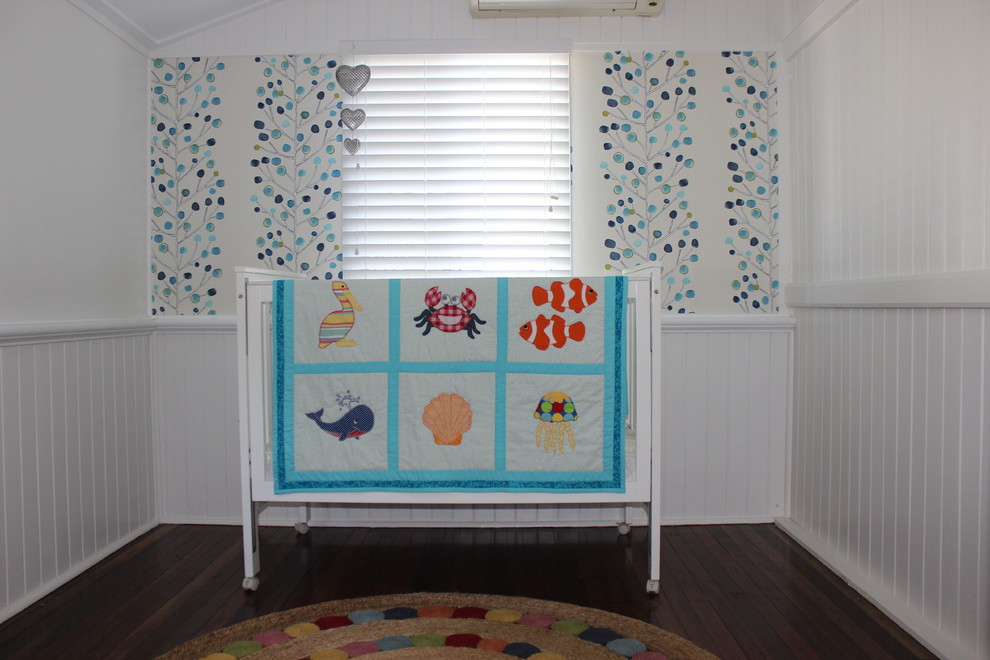 Small eclectic gender-neutral nursery in Brisbane with white walls and dark hardwood floors.