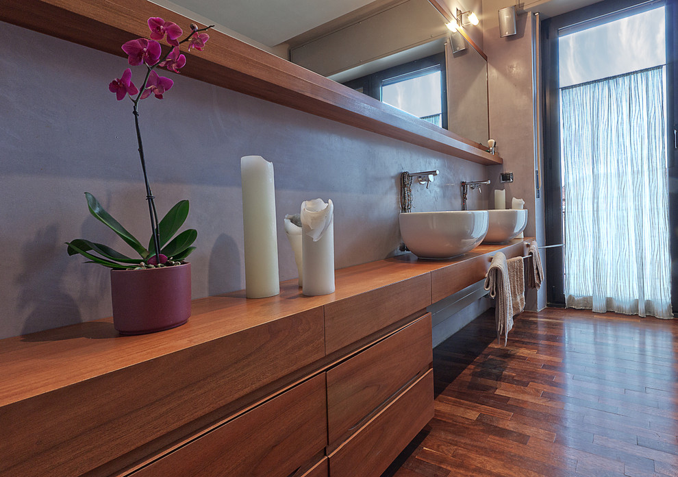 Mid-sized contemporary master bathroom in Turin with recessed-panel cabinets, medium wood cabinets, a drop-in tub, a corner shower, a wall-mount toilet, purple walls, dark hardwood floors, a vessel sink and wood benchtops.