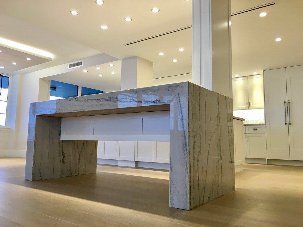 Open concept kitchen - large transitional galley light wood floor and beige floor open concept kitchen idea in Miami with an undermount sink, shaker cabinets, white cabinets, marble countertops, gray backsplash, marble backsplash, stainless steel appliances and an island