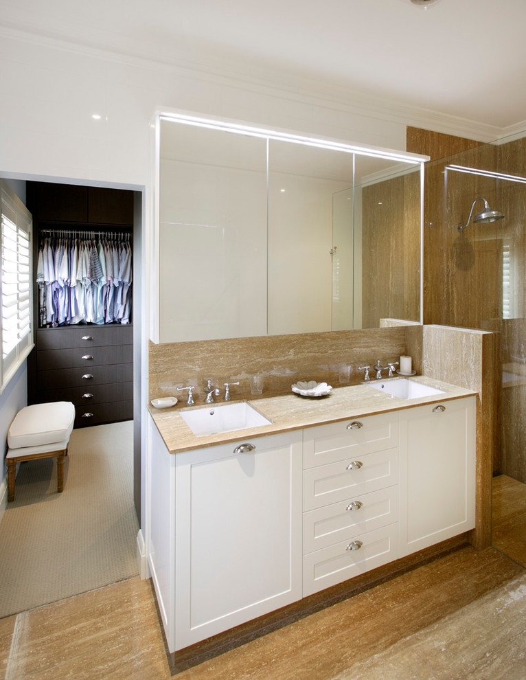 This is an example of a mid-sized contemporary master wet room bathroom in Sydney with an undermount sink, shaker cabinets, white cabinets, travertine floors, a wall-mount toilet, beige tile, marble, beige walls and marble benchtops.