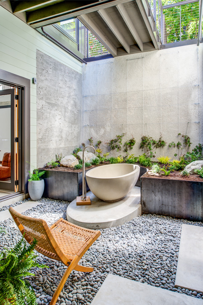 Tropical bathroom in San Francisco with a freestanding tub, grey walls and grey floor.