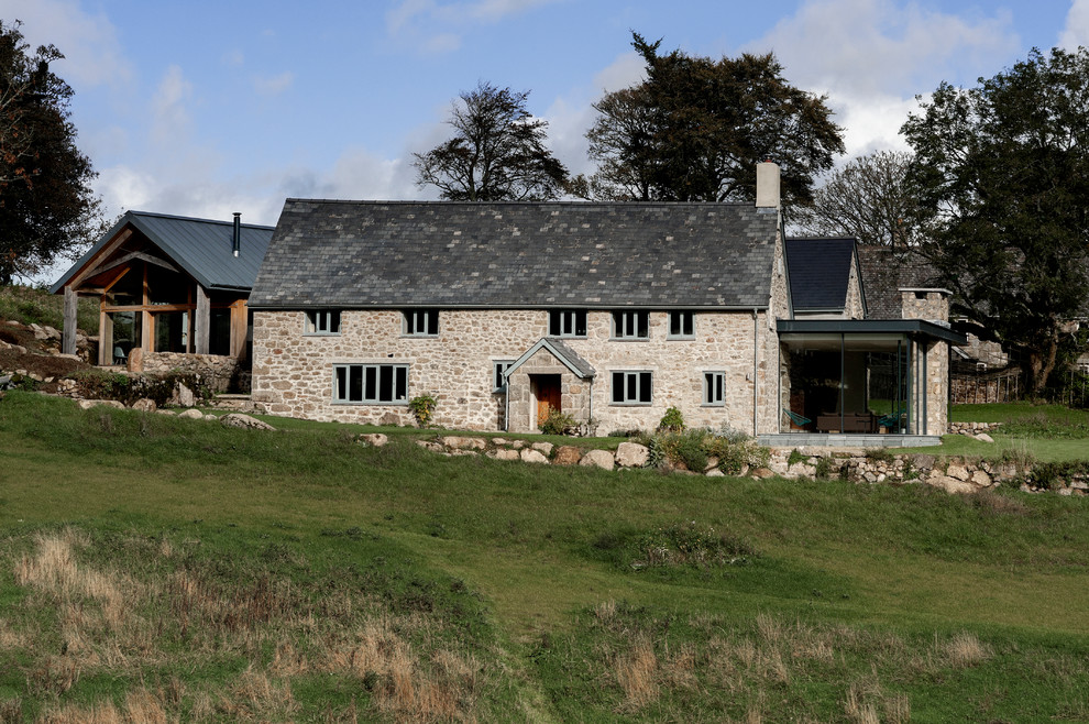 This is an example of an expansive contemporary two-storey beige exterior in Devon with stone veneer and a gable roof.