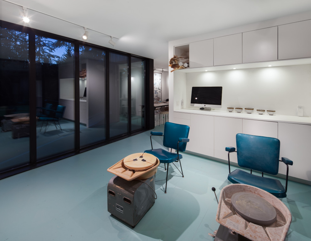Modern inredning av ett hemmastudio, med vita väggar, betonggolv och blått golv