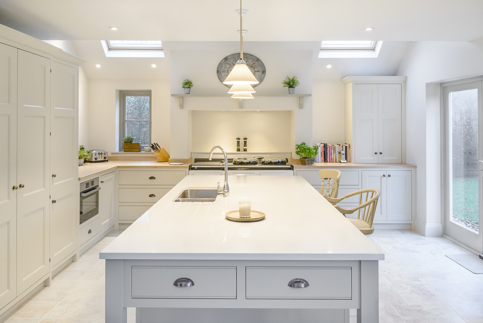 This is an example of a transitional kitchen in Oxfordshire with an undermount sink, shaker cabinets, white cabinets, stainless steel appliances and with island.