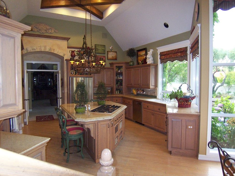 Photo of a large traditional galley eat-in kitchen in Other with an undermount sink, raised-panel cabinets, medium wood cabinets, granite benchtops, stone tile splashback, stainless steel appliances, light hardwood floors and with island.