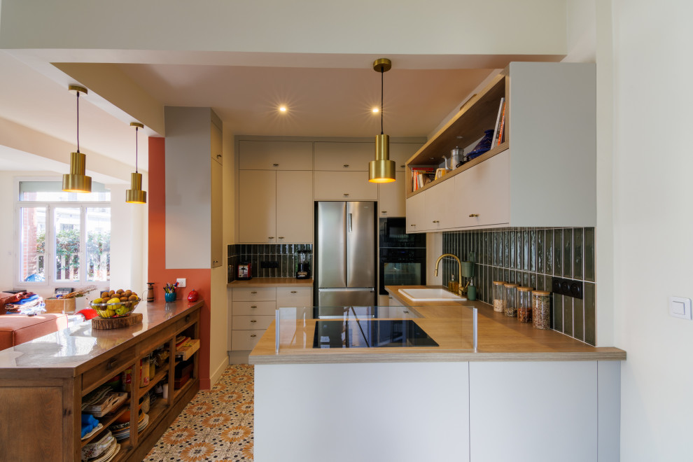 Foto di una cucina minimalista con top in legno, paraspruzzi verde, pavimento in cementine, 2 o più isole e top beige