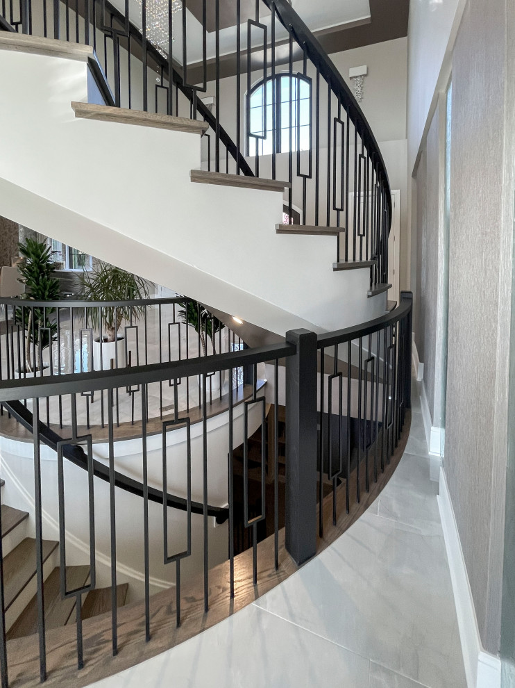This is an example of an expansive transitional wood curved staircase in DC Metro with painted wood risers, mixed railing and wallpaper.