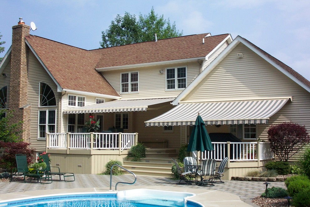 Photo of a large traditional backyard patio in Chicago with a water feature, concrete pavers and an awning.