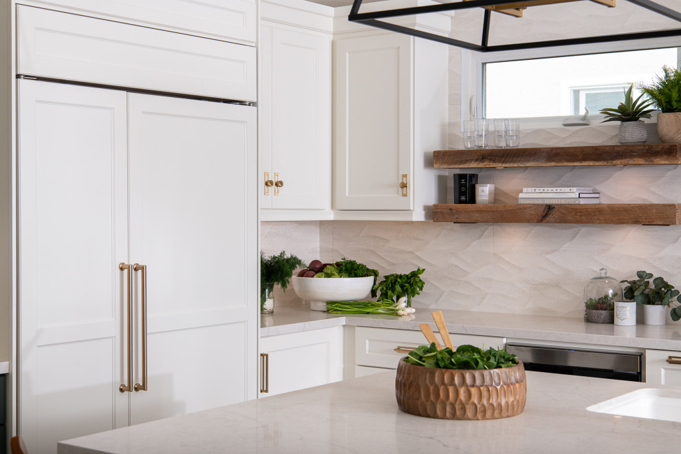 Bild på ett vintage vit vitt kök, med en undermonterad diskho, skåp i shakerstil, vita skåp, bänkskiva i kvarts, vitt stänkskydd, stänkskydd i stenkakel, rostfria vitvaror, klinkergolv i porslin, en köksö och brunt golv