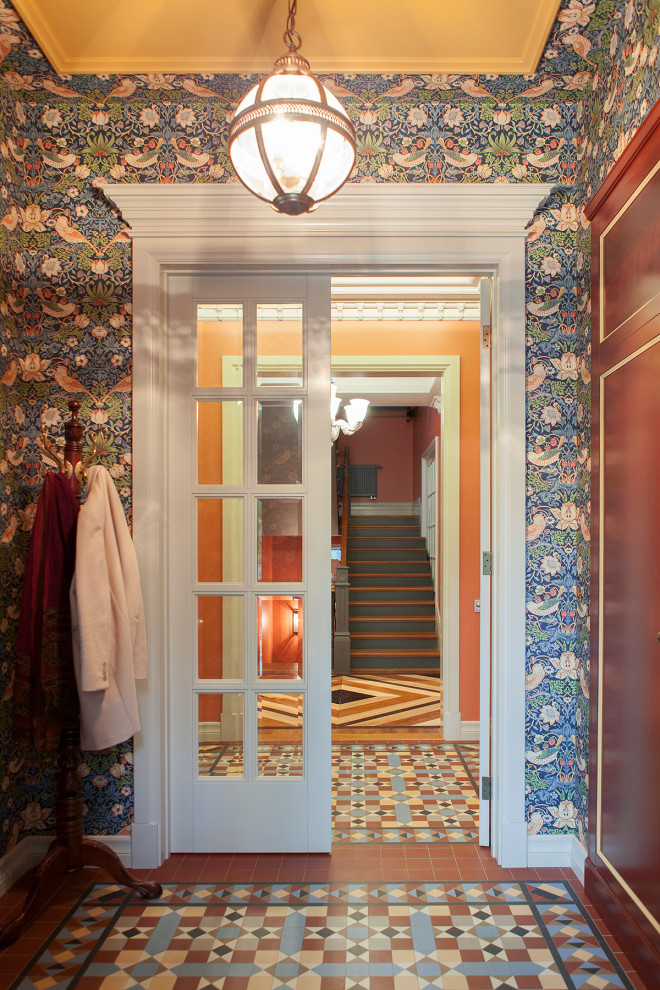 This is an example of a mid-sized eclectic mudroom in Other with red walls, ceramic floors, a single front door, a red front door, multi-coloured floor, coffered and wallpaper.