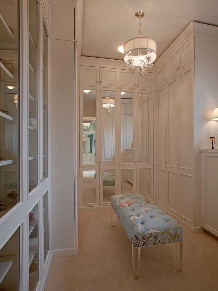 Photo of a traditional women's dressing room in Tampa with glass-front cabinets, white cabinets and carpet.