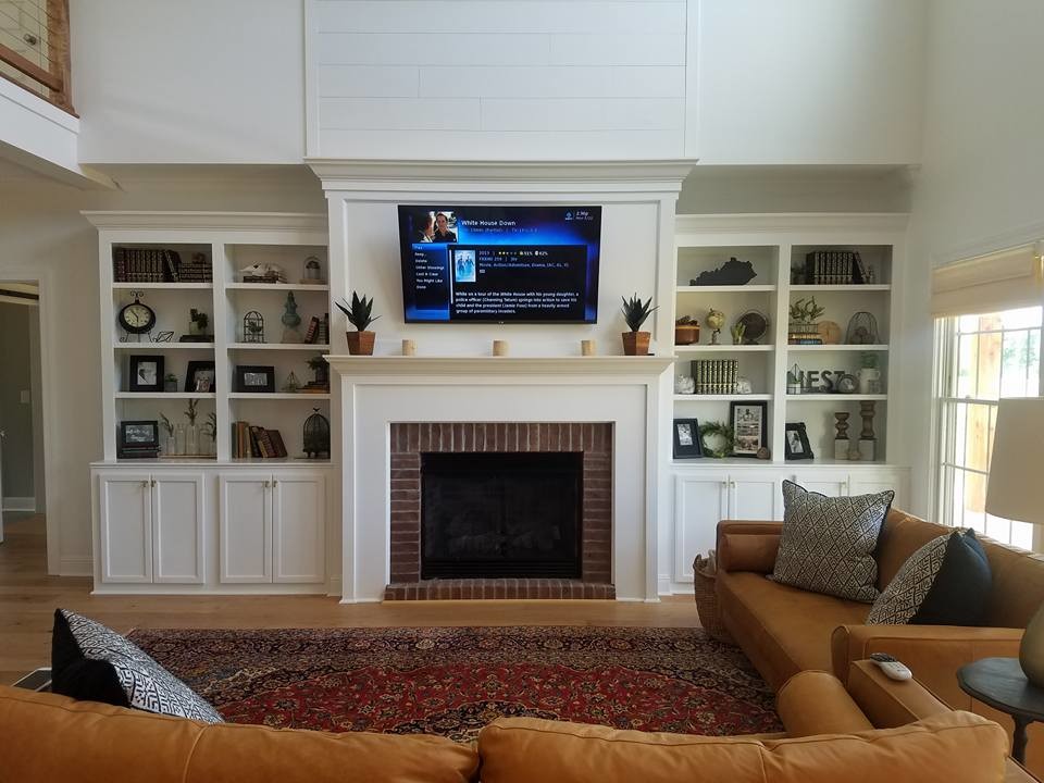 This is an example of a large traditional open concept living room in Other with a standard fireplace, a brick fireplace surround, a wall-mounted tv, white walls, medium hardwood floors and brown floor.
